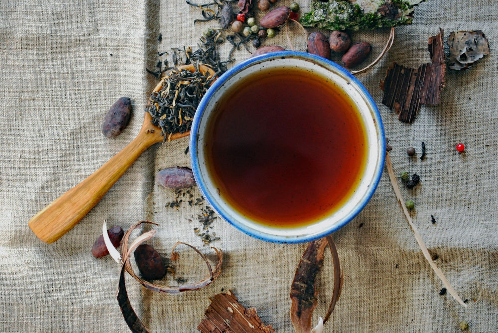 Tea cup with tea leaves and spices on a textured surface